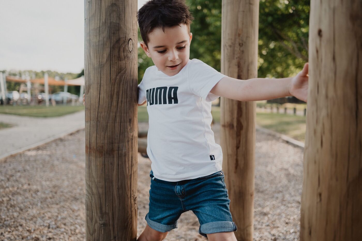 A boy leaning on wooden posts in a park